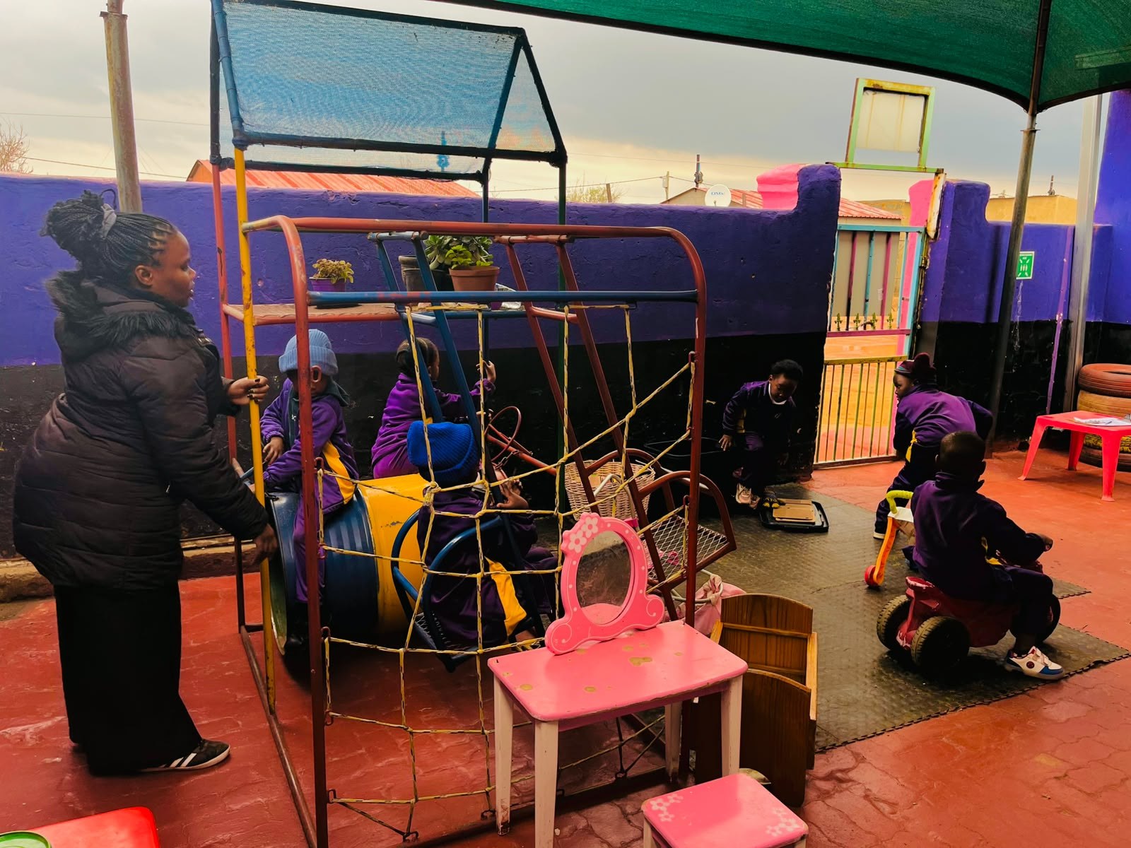 Caregiver watching children play together at Born to Shine ECD